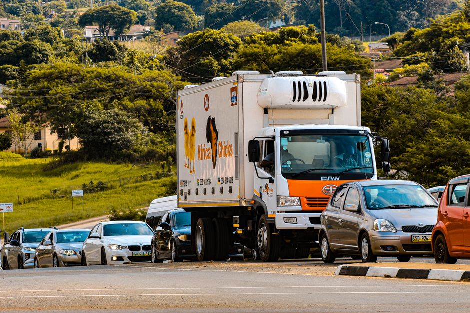 Busy traffic scene featuring a delivery truck and cars in Manzini, Eswatini.